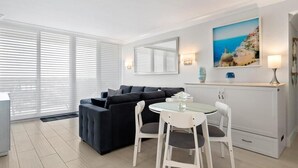 Un salon moderne avec un canapé, une table à manger et des chaises, une cheminée et un tableau accroché au mur.