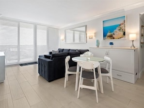 Ein modernes Wohnzimmer mit einer Couch, einem Esstisch mit Stühlen, einem Kamin und einem Bild an der Wand.