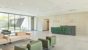A modern reception area with a green marble counter, beige sofas, and a large glass window offering a view of the outdoors. - Serene One- Luxury 1BR - The Bantree Accra Airport (Accra)