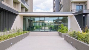 A modern building entrance with a glass facade, a central staircase, and surrounding greenery. - Serene One- Luxury 1BR - The Bantree Accra Airport (Accra)