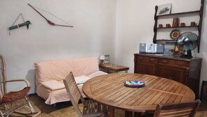 Ein gemütliches Zimmer mit einem Holzesstisch, einem Schaukelstuhl, einer Couch und einem Schrank mit Ventilator.