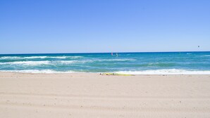 Ein Strand mit blauem Himmel, ruhiger See und sandigem Ufer.