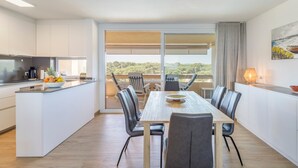 Eine moderne Küche mit Essbereich, großen Fenstern und Blick ins Freie.