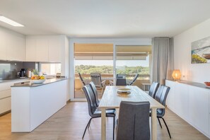 A modern kitchen with a dining area, large windows, and a view of the outdoors. - Holiday Home 'Frontline Apartment with Community' with Sea View, Shared Pool and Wi-Fi (Pals)