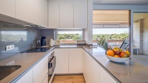 Eine moderne Küche mit Blick ins Freie, eine Obstschale auf der Arbeitsfläche und ein Fenster mit Grünblick.