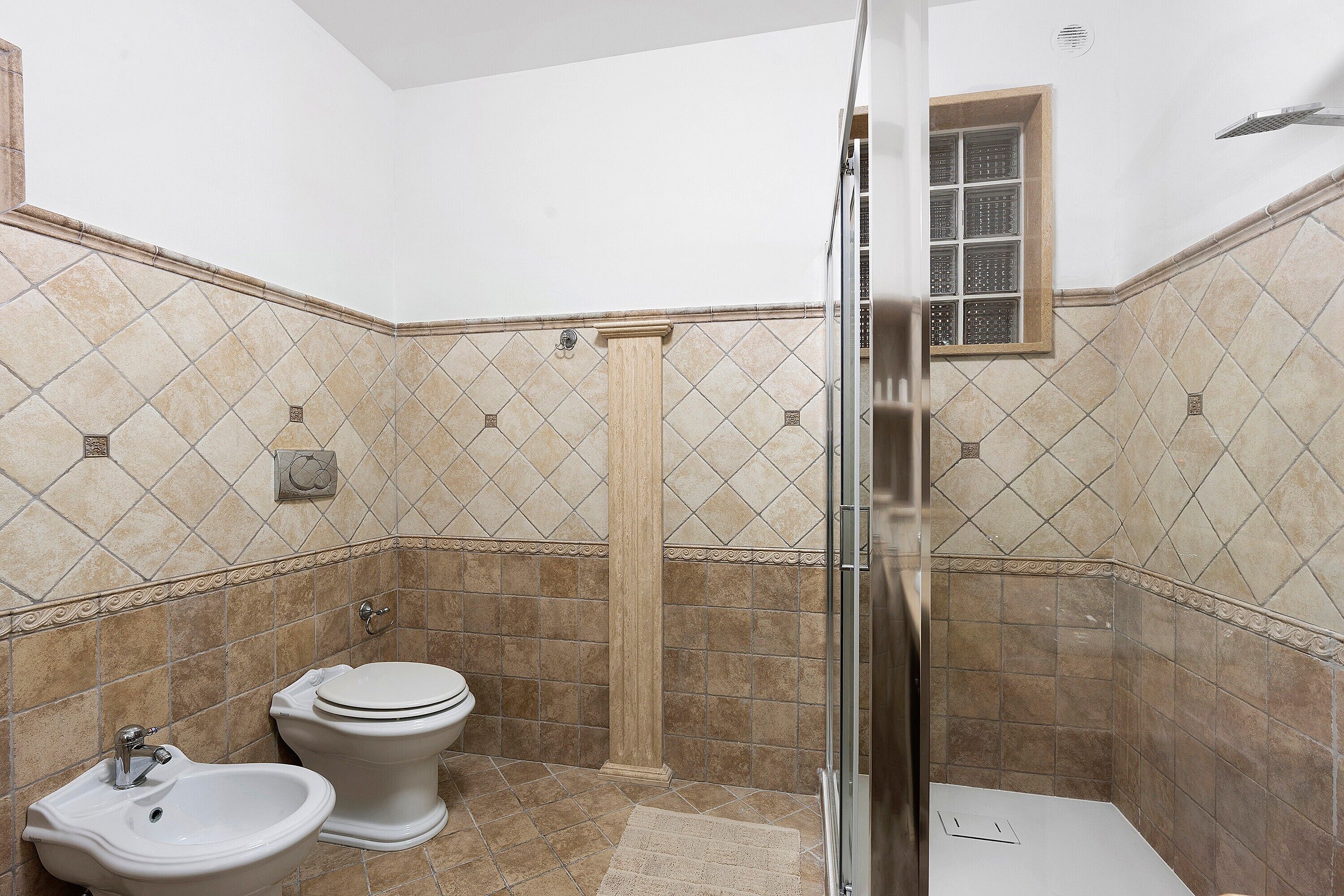 Een badkamer met een douche, toilet en toiletbril.