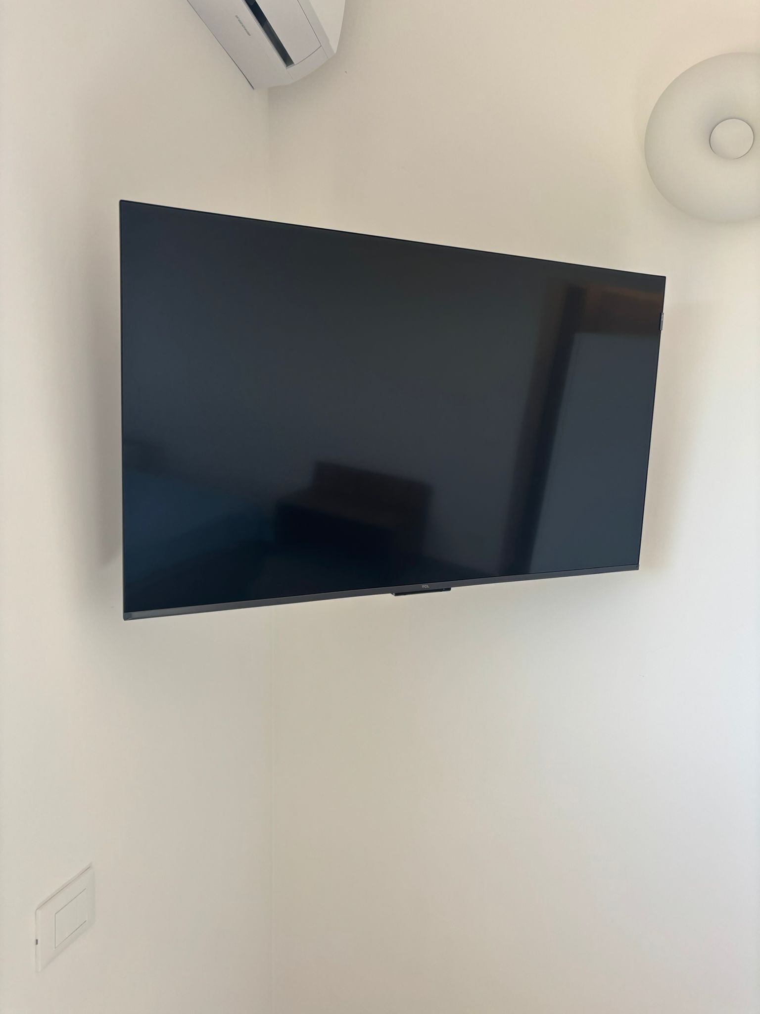 Seinälle asennettu litteänäyttöinen televisio, ja seinä on maalattu valkoiseksi.