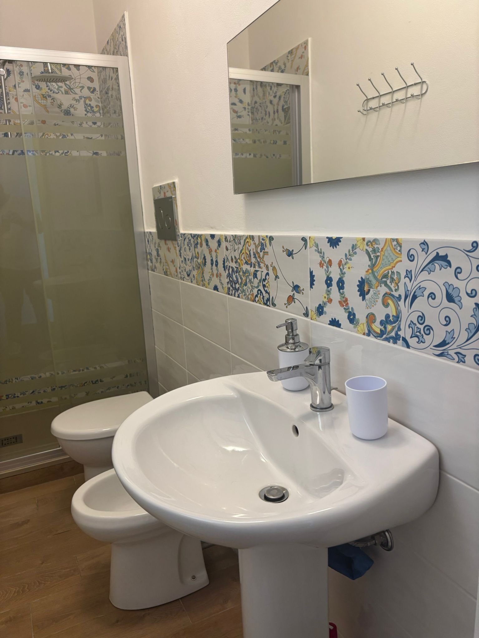 A bathroom with a white sink, a mirror, a toilet, and a shower area.