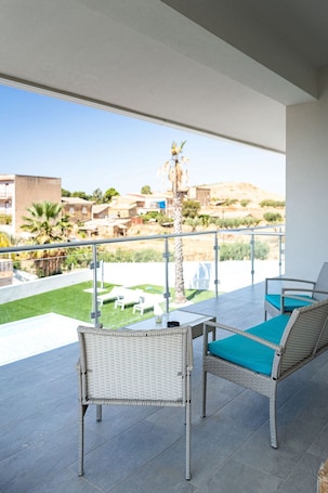 A balcony with wicker furniture and a view of a landscaped area.