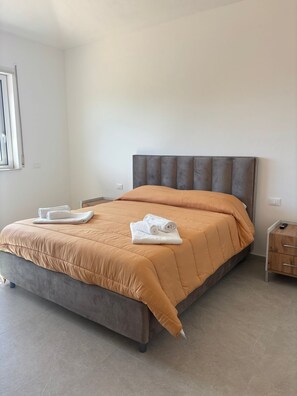 Un dormitorio moderno con una cama grande, una mesita de noche y un ventanal.