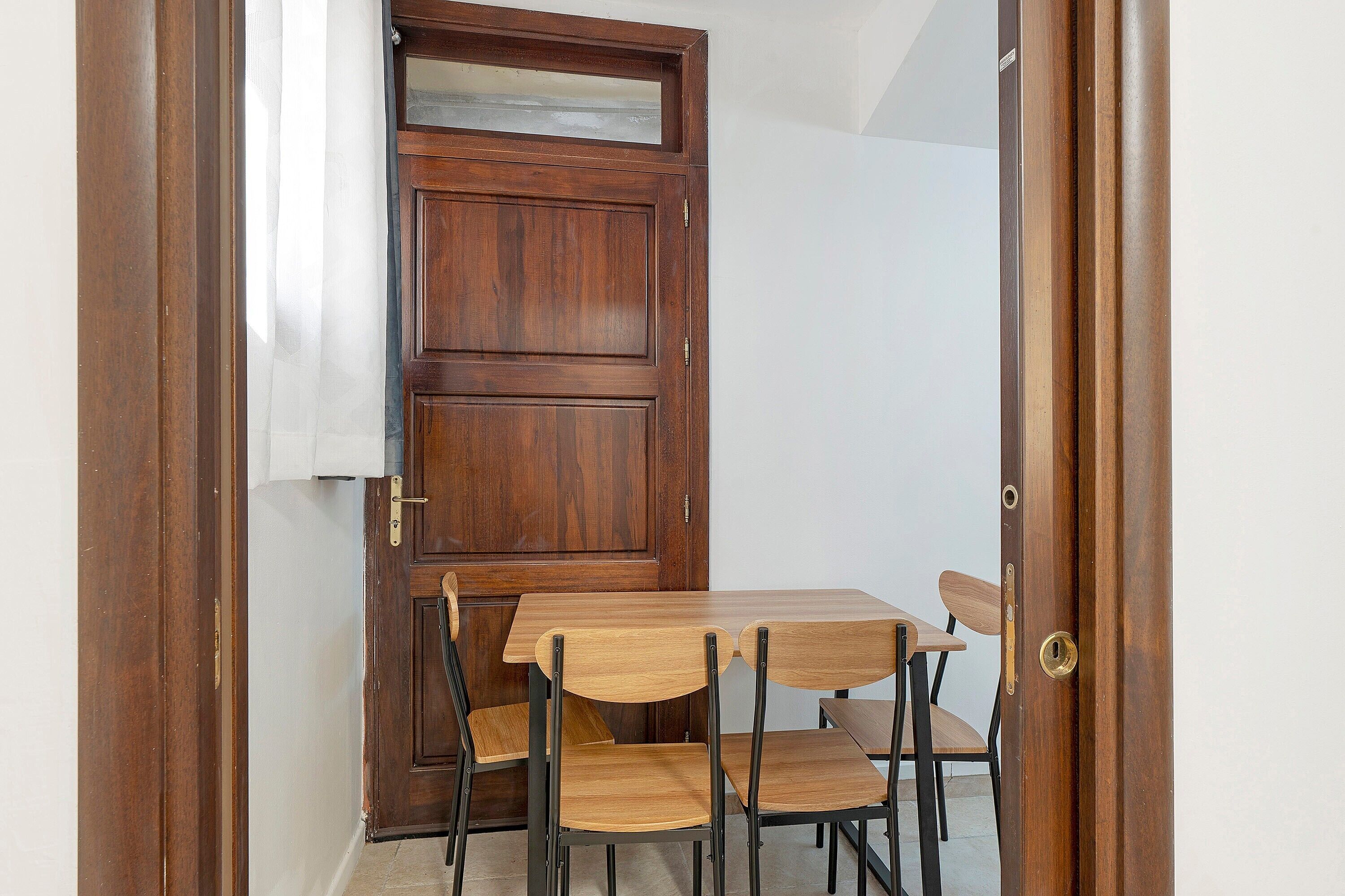 A wooden door with a glass panel, a wooden table, and four chairs.
