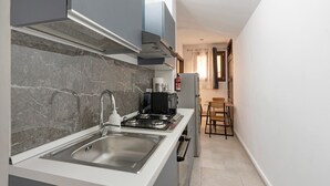 Een moderne keuken met een ingebouwd gasfornuis, een roestvrijstalen spoelbak en een compacte eethoek met een tafel en stoelen.