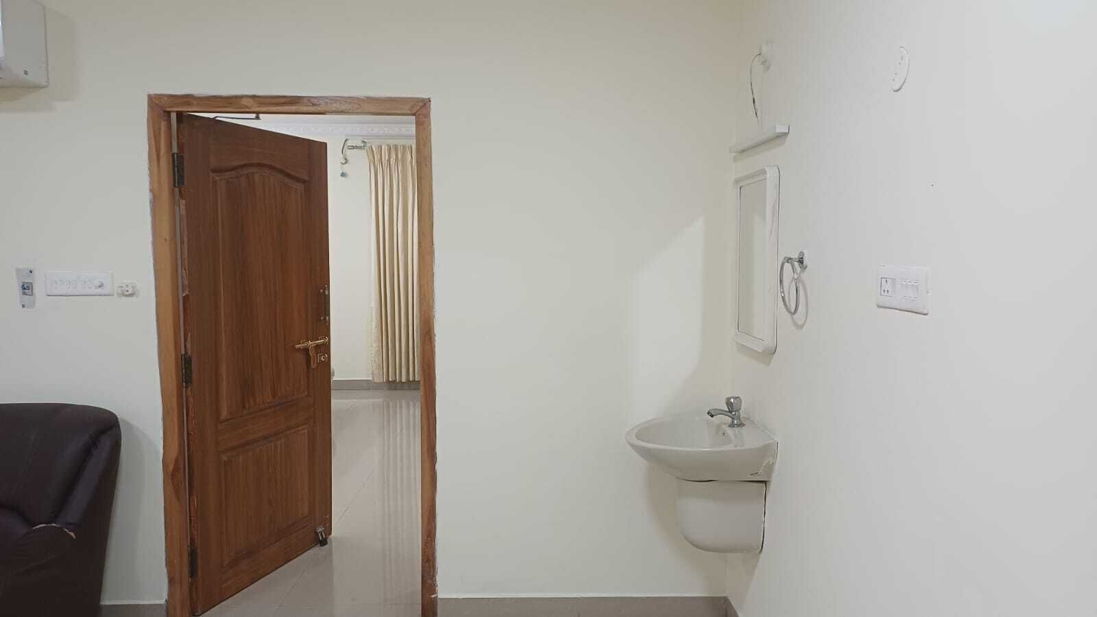 Una habitación con una puerta de madera, un lavamanos blanco y un espejo en la pared.