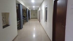 A corridor with a tiled floor, blue columns, and a wooden door. - Hotel Tamilnadu Trichy (Tiruchirappalli)