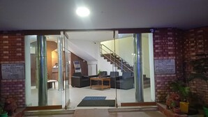 A hotel lobby with a reception desk, seating area, and a staircase. - Hotel Tamilnadu Trichy (Tiruchirappalli)
