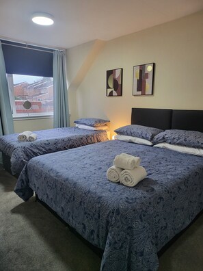 A hotel room with two beds, a window with curtains, a ceiling light, and two wall art pieces. - 3-Bed Detached Home. Contractors & Families. Quiet cul-de-sac. Parking. (Wolverhampton)