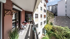 Un balcone con tavolo e sedie, una pianta in vaso e vista sugli edifici vicini.
