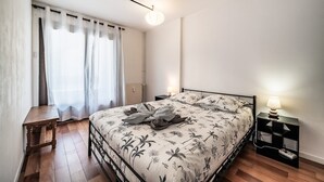 Una camera da letto con un letto, comodino, lampada e vista sull'esterno.