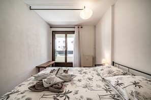 Un dormitorio con cama, banca, lámpara colgante y vista a través de una puerta.