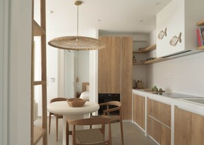 A modern kitchen with wooden cabinets, a white countertop, and a hanging light fixture. - Sto Lofo | Design Villa w/ Pool & Views | Plakias & Preveli (Τοπική Κοινότητα Ασωμάτου)