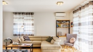 Een moderne woonkamer met een modulaire bank, een grijze fauteuil, een salontafel en een vloerlamp.