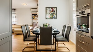 Een moderne eetruimte met een ronde tafel, zwarte stoelen en een keuken met roestvrijstalen apparatuur.