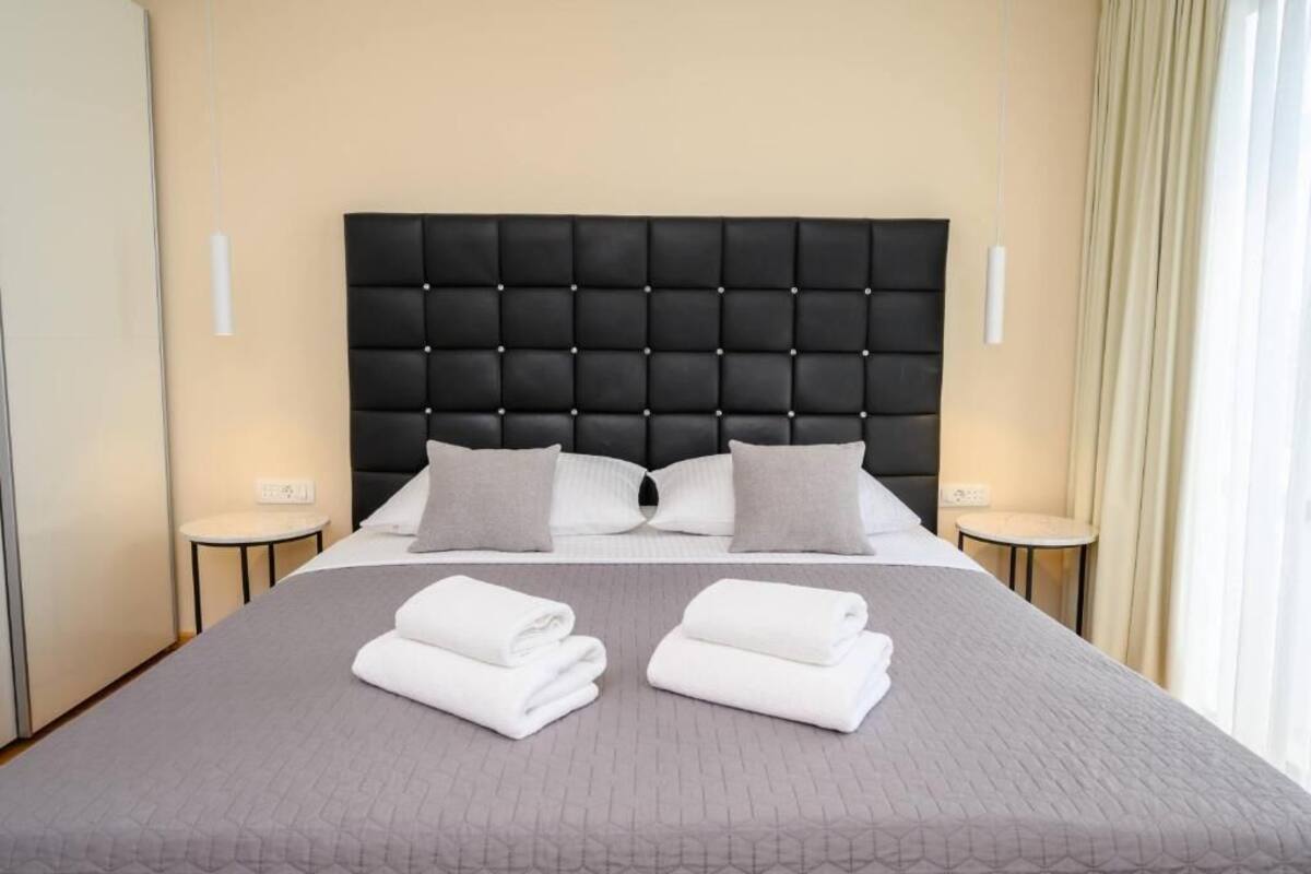 A hotel room with a large bed, two bedside tables, and a headboard.