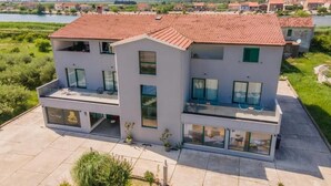 Ein modernes, zweistöckiges Gebäude mit rotem Ziegeldach, großen Fenstern und einem Balkon.