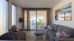 A modern living room with a sofa, armchair, and coffee table, a balcony with outdoor furniture, and a painting on the wall. - Beachfront Premium Terraza piscina Javea (Javea)