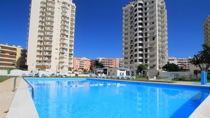 A swimming pool with a clear blue water surface, surrounded by high-rise residential buildings. - Apt. S. Lourenço Beachfront – No Sea View, Shared Pool, Balcony & Wi-Fi (Armação de Pêra)