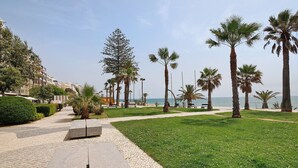 A paved walkway with benches, palm trees, and a view of the sea. - Apt. S. Lourenço Beachfront – No Sea View, Shared Pool, Balcony & Wi-Fi (Armação de Pêra)