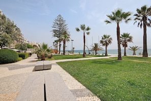 A paved walkway with benches, palm trees, and a view of the sea. - Apt. S. Lourenço Beachfront – No Sea View, Shared Pool, Balcony & Wi-Fi (Armação de Pêra)