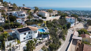 Ett bostadsområde med hus, en swimmingpool och utsikt över havet.