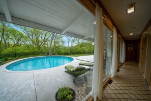 A covered swimming pool with lounge chairs and a pathway leading to a building. - Luxury Pool Home Near FIFA 2026 World Cup KC (Kansas City)