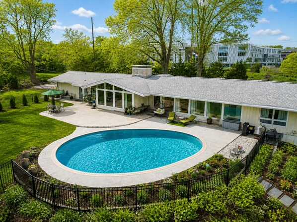 A modern house with a swimming pool, a covered patio, and a well-maintained lawn. - Luxury Pool Home Near FIFA 2026 World Cup KC (Kansas City)