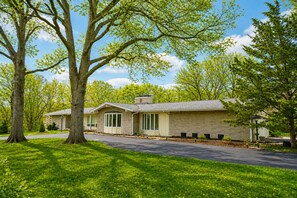 A two-story house with a brick exterior, large windows, and a driveway. - Luxury Pool Home Near FIFA 2026 World Cup KC (Kansas City)