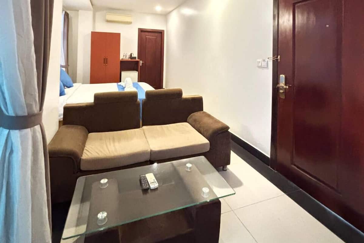 Una sala de estar con un sofá, una mesa de centro de vidrio, una puerta y una lámpara de techo.