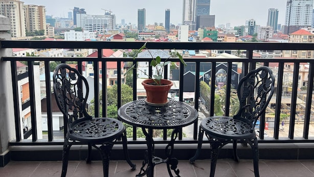 Un balcon agrémenté de deux fauteuils décoratifs, d’une petite table et d’une plante en pot.