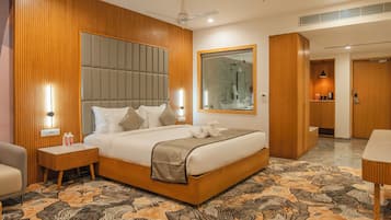 A modern hotel room with a large bed, wooden paneling, a large mirror, and a bathroom visible through an open door.