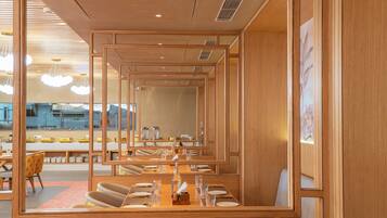 Ein Restaurant mit Spiegelwänden, Holzmöbeln und Blick auf die Küche.