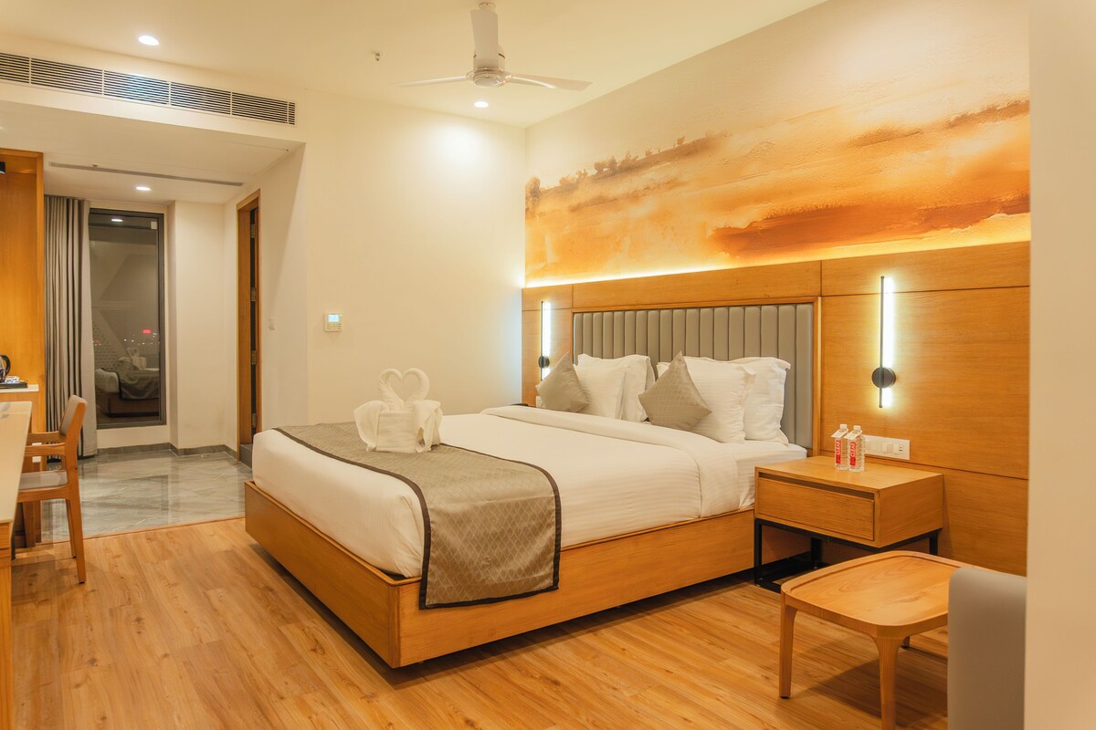 A modern hotel room with a wooden bed, a desk, and a chair.