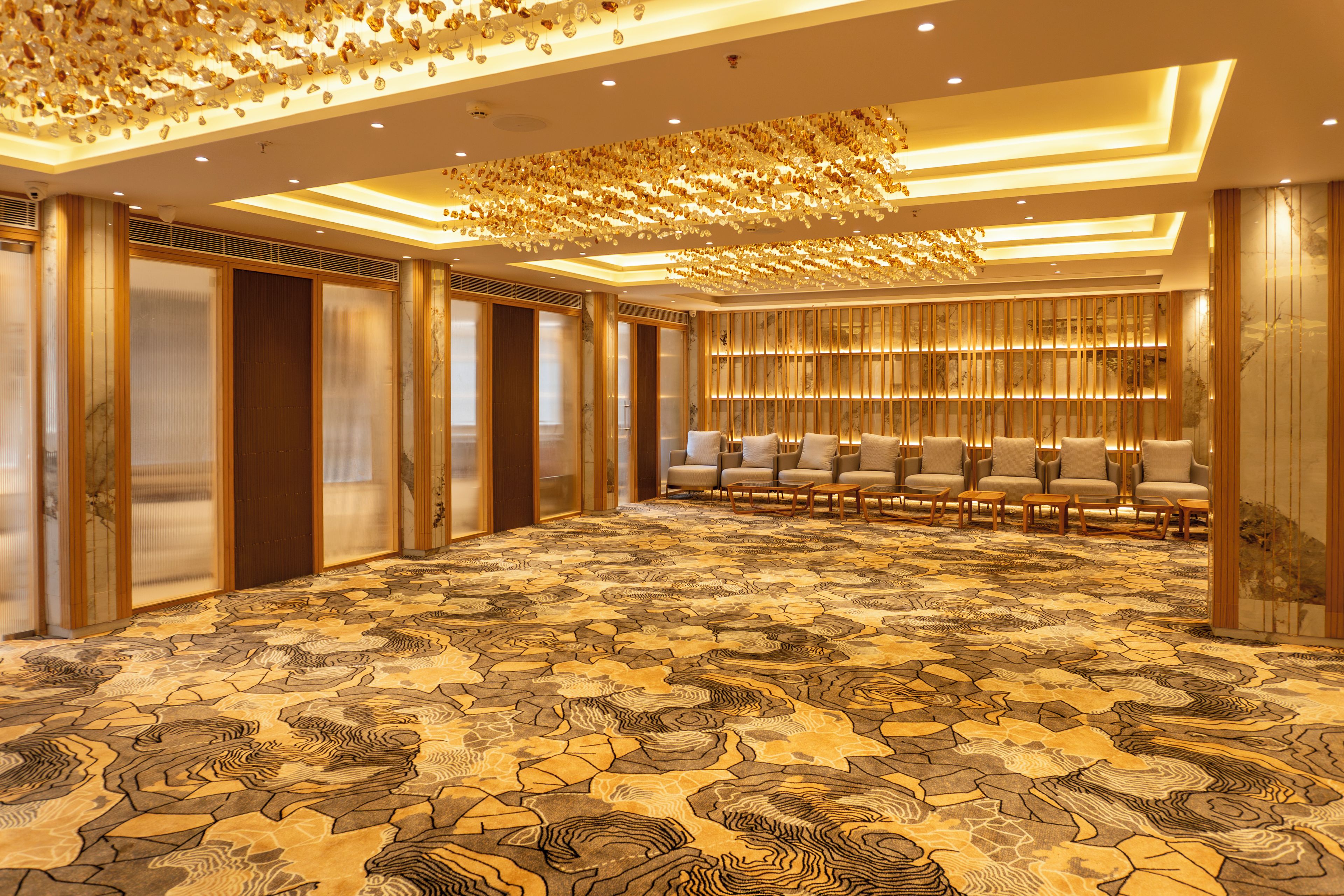 A spacious hotel lobby with a patterned carpet, seating area, and a decorative ceiling.