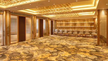 A spacious hotel lobby with a patterned carpet, seating area, and a decorative ceiling.
