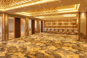 Un amplio vestíbulo de hotel con alfombra estampada, zona de estar y techo decorativo.