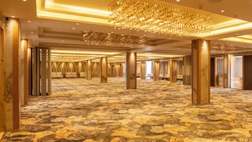 A spacious hotel lobby with a patterned carpet, large columns, and a chandelier.