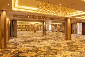 Un amplio vestíbulo de hotel con alfombra estampada, grandes columnas y un candelabro.
