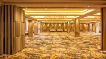 A spacious hotel lobby with a patterned carpet, a chandelier, and a row of seating.