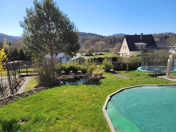 A residential area with a swimming pool, a trampoline, and a house with a sloped roof.