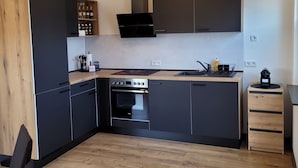 Una cocina moderna con armarios oscuros, horno empotrado y encimera de madera.