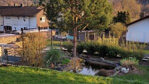 Un barrio residencial con casas, un jardín con un estanque y una colina al fondo.